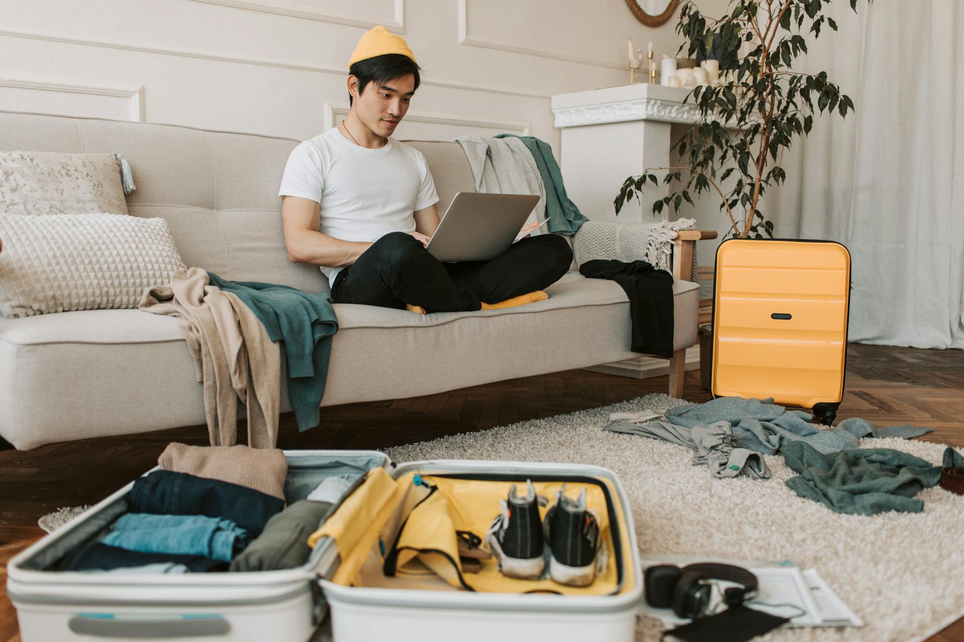 Koffer auf dem Boden, Mann auf der Couch am Laptop